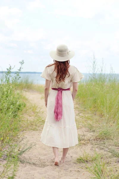 Vintage vrouw met hoed lopen op strand pad — Stockfoto