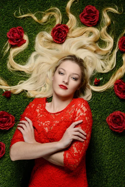 Mulher em vestido vermelho que coloca na grama — Fotografia de Stock