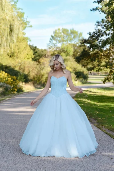 Mujer joven en vestido de bola azul en el jardín — Foto de Stock