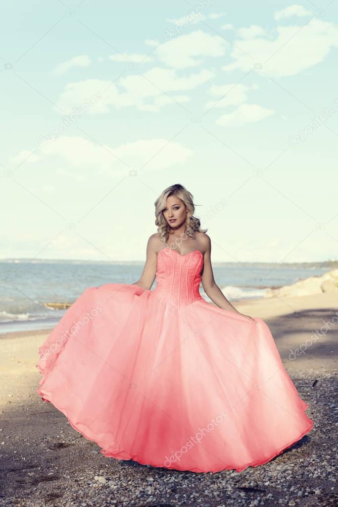 young blonde woman at the beach with red tulle ball dress