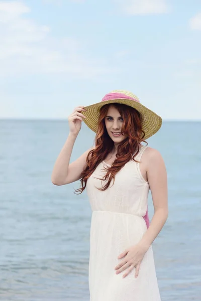 Portrait redhead woman at beach wearing hat — Stock Photo, Image