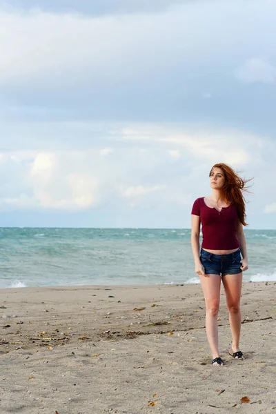 ビーチで風に吹かれて髪赤毛の女性 — ストック写真