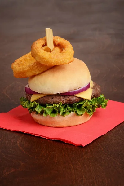 带洋葱环的汉堡包 上面放红色餐巾 — 图库照片
