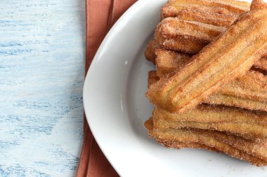 Yakın plan tarçınlı churros tabağı.