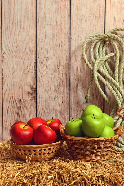 用绳子把红苹果和绿苹果捆在干草捆上 — 图库照片