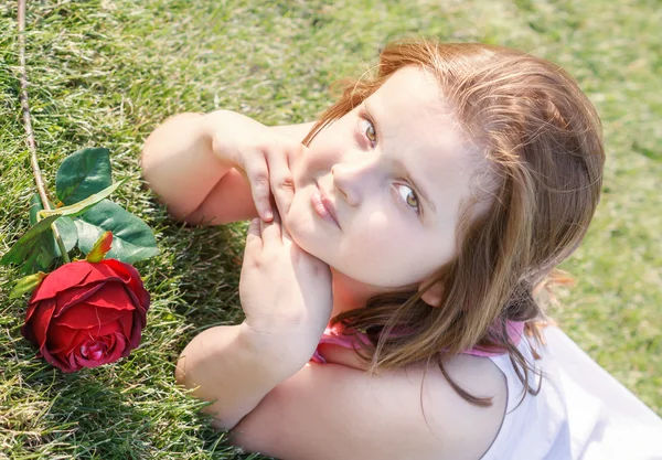 Meisje liggen op gras met roos — Stockfoto