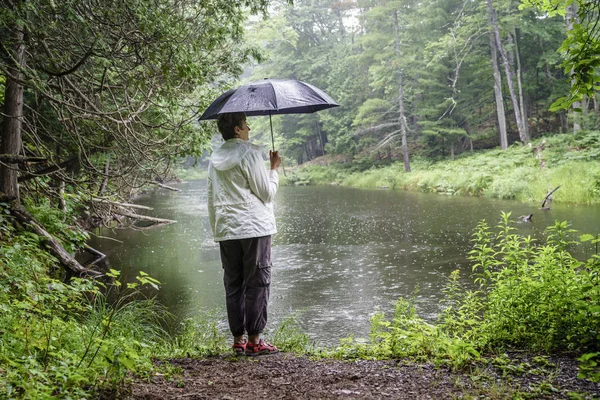 Vrouw met paraplu op de oever van de rivier — Stockfoto