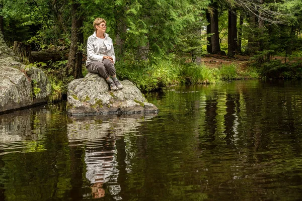 La mujer está sentada en una roca — Foto de Stock