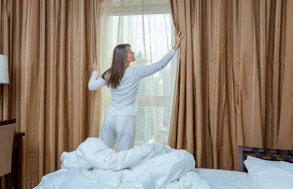 Mujer madura abriendo cortinas —  Fotos de Stock