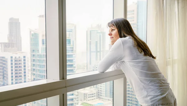 Rijpe vrouw kijkt uit het raam ik — Stockfoto