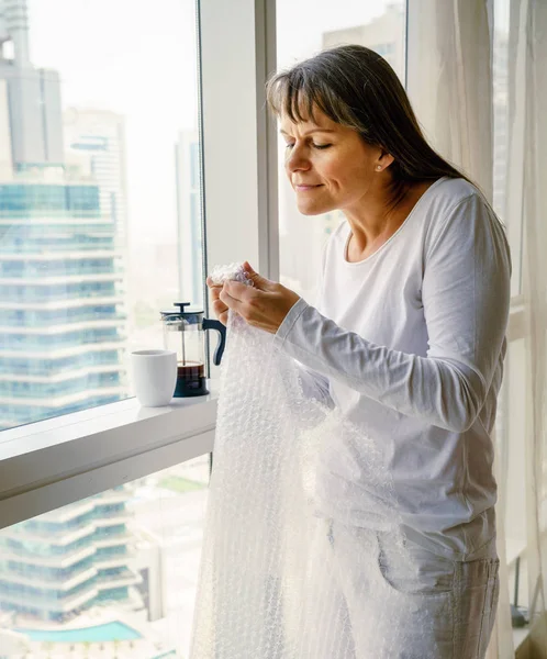 Rijpe vrouw popping bubble wrap — Stockfoto