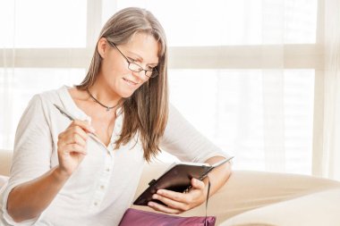 Olgun kadın onun evinde bir kanepede oturan günlüğünü notlar yapıyor