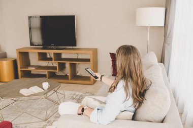 Kanepede televizyon izlemeye hazırlanan bir kadın.