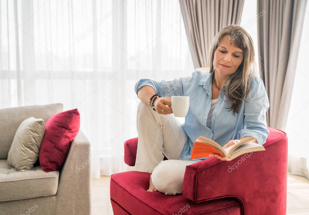 Mature woman relaxing with a book in her urban apartment