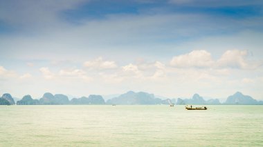 Andaman Denizi 'nde küçük balıkçı tekneleri ve ufukta Krabi kıyıları var.