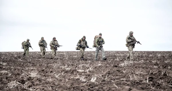 Soldados del ejército marchan en campo fangoso — Foto de Stock