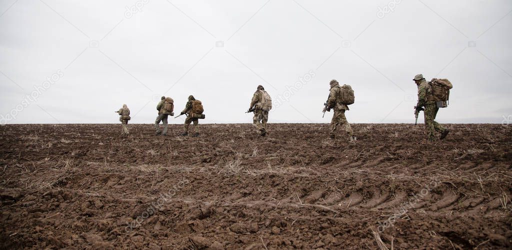 Army soldiers group on march in muddy field