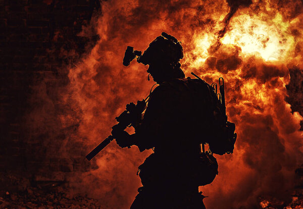 Силуэт солдата на фоне огня и дыма
