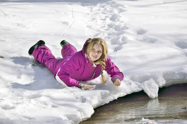 Chica feliz tumbada en la nieve en invierno —  Fotos de Stock