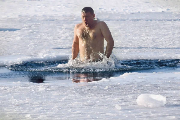 Jonge man zwemmen in het meer van de winter in het ijsgat — Stockfoto