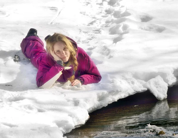 Chica feliz tumbada en la nieve en invierno — Foto de Stock