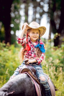 Park midilli sürme kovboy şapkalı örgü ile küçük kız
