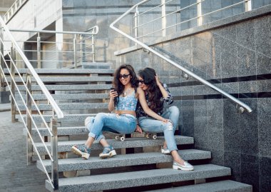 Kaykay posig şehir ve having fun çevresinde iki genç kızla