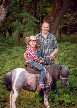 Kovboy şapkası binme midilli küçük kız babasıyla Park