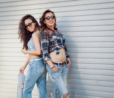 İki genç kız açık havada kaykay ile poz