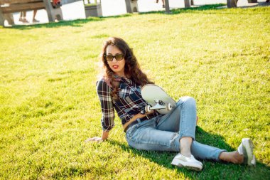 Genç esmer kız açık havada kaykay ile poz