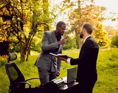 Parkta iş adlı iki genç çok kültürlü businessmans. Uzak iş kavramı.