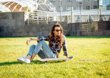 Genç esmer kız açık havada kaykay ile poz