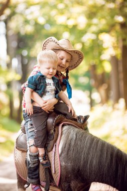 Küçük kız ve at binme erkek kardeşi yeşil park midilli