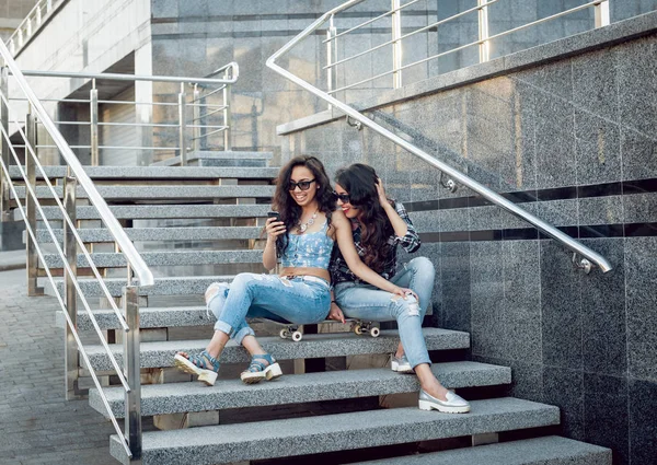 Kaykay posig şehir ve having fun çevresinde iki genç kızla