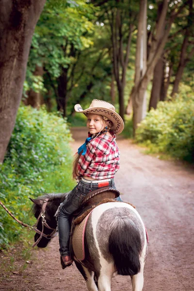 小女孩与辫子在牛仔帽骑小马在公园 — 图库照片