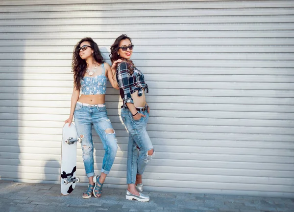 İki genç kız açık havada kaykay ile poz