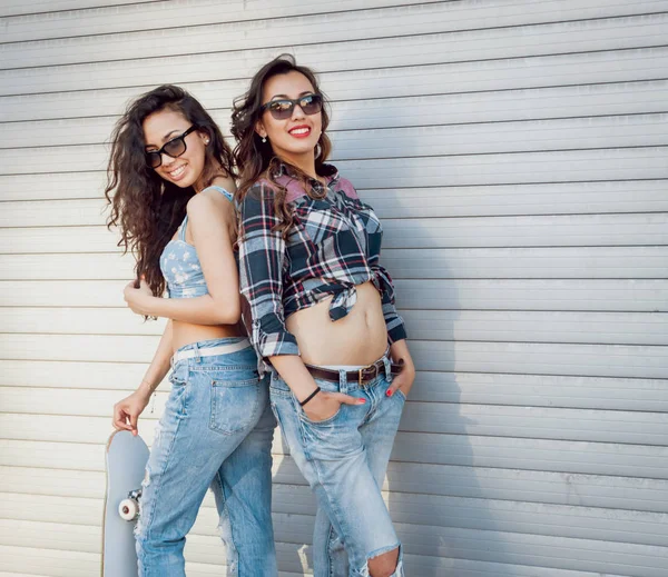 İki genç kız açık havada kaykay ile poz