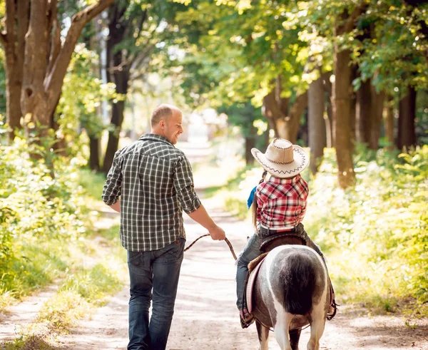 Kovboy şapkası binme midilli küçük kız babasıyla Park