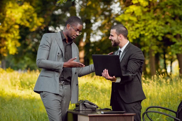 İki genç çok kültürlü iş adamları iş park yerinde. Uzak iş kavramı.