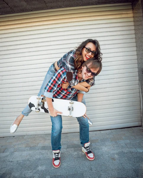 Jovem Casal Com Skate Contra Portões Rolantes — Fotografia de Stock