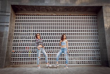 Kaykay posig şehir ve having fun çevresinde iki genç kızla