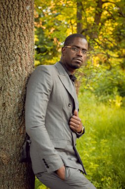 Park ağaç yakınındaki gri elbiseli genç Afrika adam
