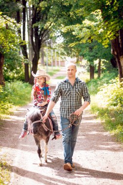 Kovboy şapkası binme midilli küçük kız babasıyla Park