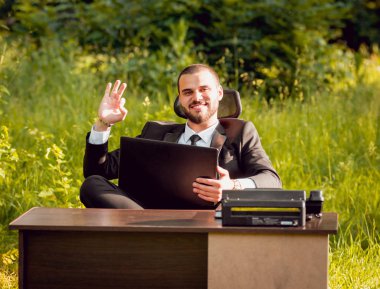 Genç işadamı park içinde işte. Uzak iş kavramı.