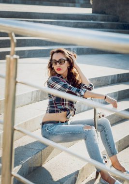 Genç esmer kız açık havada kaykay ile poz