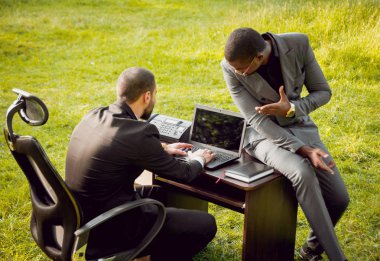 Parkta iş adlı iki genç çok kültürlü businessmans. Uzak iş kavramı.