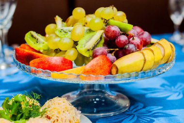 meyve. muz, üzüm, kivi, elma bir cam tabakta