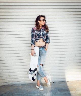 Genç esmer kız açık havada kaykay ile poz