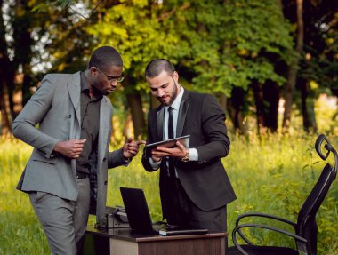 Parkta iş adlı iki genç çok kültürlü businessmans. Uzak iş kavramı.