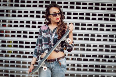 Genç esmer kız açık havada kaykay ile poz